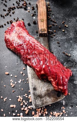 Raw Skirt, Machete Steak On A Meat Cleaver. Black Background. Top View