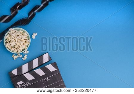 Clapper Board With Popcorn And Film Strip On A Bright Blue Background With Copy Space. For Articles 