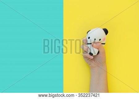 Flat Lay Antistress Toy Squish Black White Big Panda Squeezed In Hand.bright Yellow Blue Background.