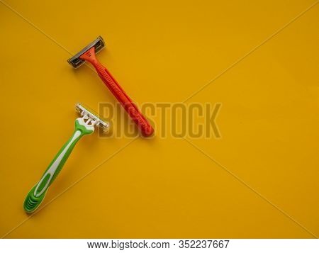 Two Unisex Razors On The Yellow Background. Top View. Copy Space