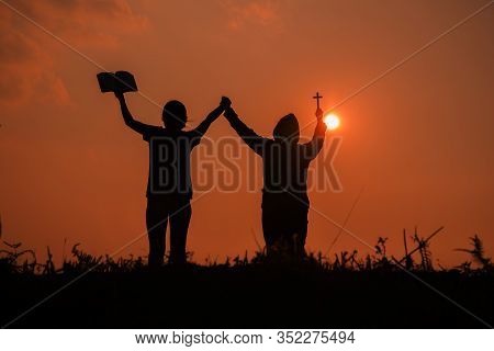 Silhouette Of Two Teen Girls Praying To God With The Bible.