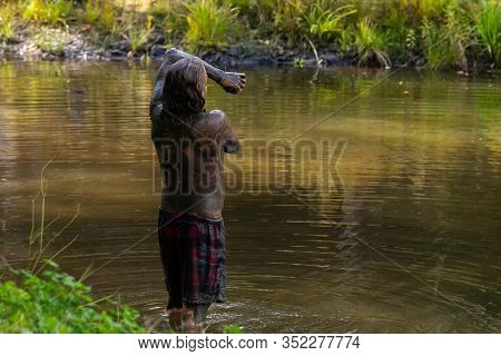 A Man Is Seen Bathing In Dirty Mud Water During A Forest Retreat Connecting With Nature For Healthy 