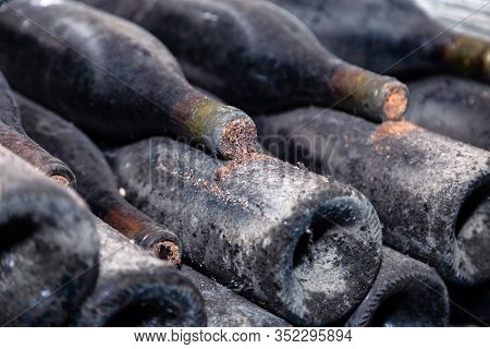 Closeup Dark Dusty Wine Bottles With Old Crumbly Cork. Long Aging, Musty Winery Vault, Rare Ancient 
