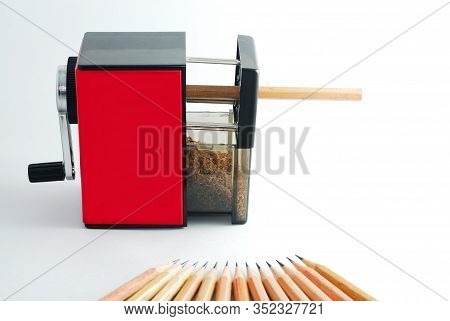Rotary Pencil Sharpener. Red Black Rotary Pencil Sharpener With Brown Pencil On White Background.