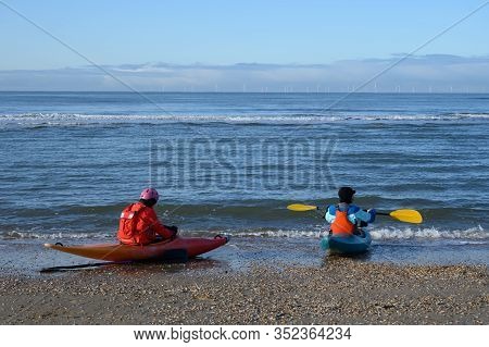Unidentified People In Kayaks Going In To Water On North Sea Sandy Beach During Low Tide Near Castri