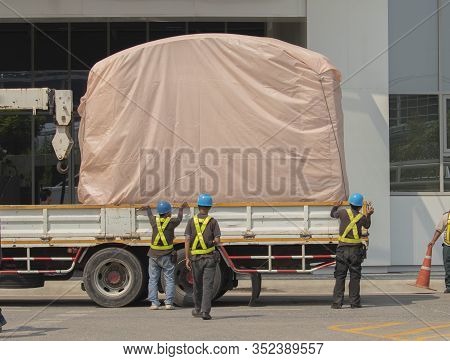 Orange Forklift Is Lifting The Train Head, Covering The Pink Cloth, With The Workers Wearing Work Cl