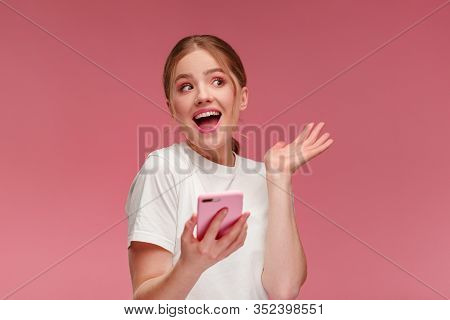 The Best Day Ever. Surpised Young Redhead Woman Holding Pink Smartphone, Smiling And Expressing Posi