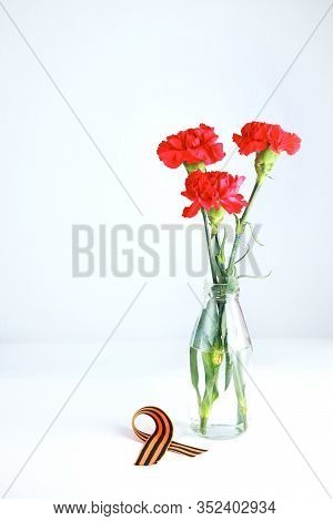 Three Red Carnations And St. George Ribbon (russian Symbol) On A White Uniform Background. Greeting