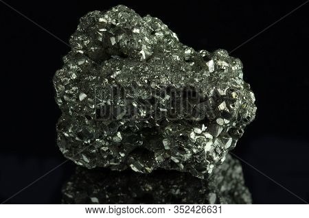 A Cluster Of Pyrite Crystals. Isolated On A Black Mirror Background.