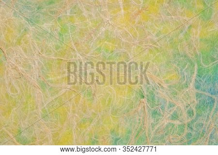 Natural Thai mulberry kozo paper against green, blue and yellow marbled paper