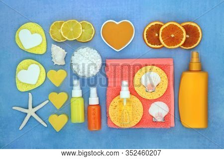 Summer spa beauty treatment with fresh blood orange fruit, after sun lotion, moisturising creams & oil, ex foliation salts, soap & cleansing products. Flat lay on blue background.