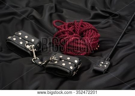 Leather Handcuffs, Shibari Rope And Stack On Black Background. Accessories For Adult Sexual Game. Bd