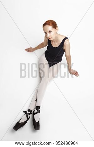 Sport Ideas. Relaxing Caucasian Professional Ballet Dancer In Body Suit  And Pointes Shoes Posing Ag