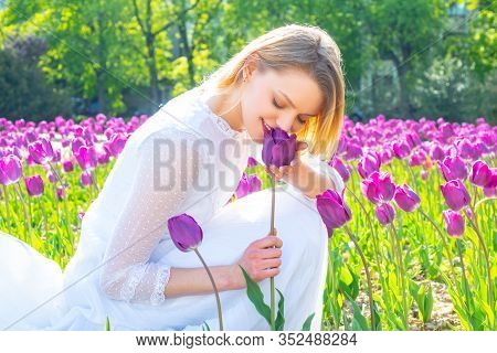 Beauty Spring Woman With Tulip Flovers. Young Woman Relaxing In The Tulips Fields