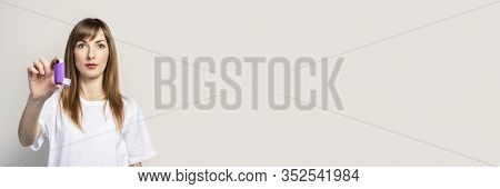 Young Woman Holds An Inhaler In A Hand On A Light Background. Banner. Concept For Easier Breathing, 