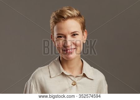 Portrait Of Smiling Young Woman With Short Pixie Haircut Looking Cheerfully At Camera While Standing