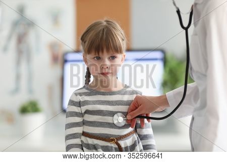 Portrait Of Serious Little Patient On Examining Of Experienced Pediatrician. Practitioner Listening 