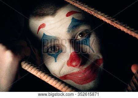 Close-up Portrait Of A Joker Man. Stock Photo Makeup Joker In A Horror Room.
