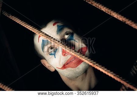 Close-up Portrait Of A Joker Man. Stock Photo Makeup Joker In A Horror Room.