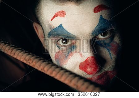 Close-up Portrait Of A Joker Man. Stock Photo Makeup Joker In A Horror Room.