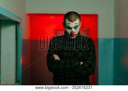 Close-up Portrait Of A Joker Man. Stock Photo Makeup Joker In A Horror Room.