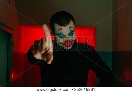 Close-up Portrait Of A Joker Man. Stock Photo Makeup Joker In A Horror Room.