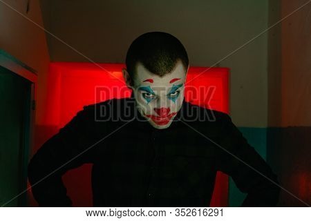 Close-up Portrait Of A Joker Man. Stock Photo Makeup Joker In A Horror Room.