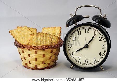 Black Classic Round Clock With Arrows And A Small Basket With Cookies. Time For A Pleasant Breakfast