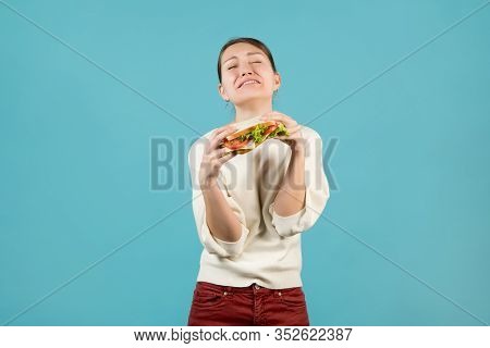 A Young Woman Suffers And Holds A Sandwich In Her Hands.