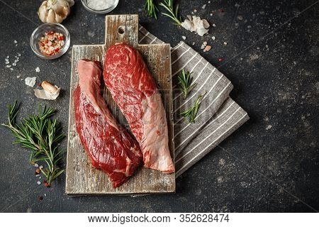 Raw Fresh Steak Sirloin Flap Served With Rosemary, Garlic And On Wooden Cutting Board. Black Angus B