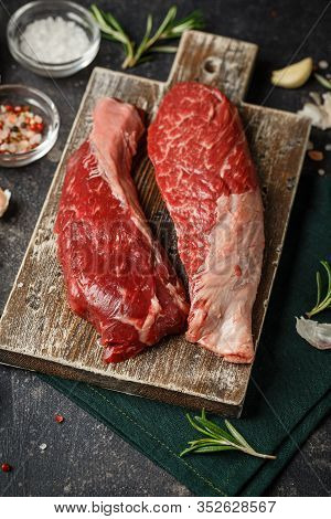 Raw Fresh Steak Sirloin Flap Served With Rosemary, Garlic And On Wooden Cutting Board. Black Angus B