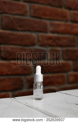 Bottle Of Serum, Hyaluronic Acid, Botulin On White Wooden Table. Grunge Red Brick Wall For Your Logo