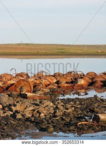 Old Rusty Iron Barrels On The Background Of The Arctic Lake. Environmental Disaster