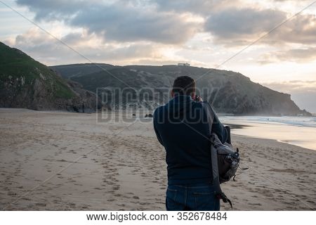 Man Taking A Photo Of Praia Do Amado Beach In Costa Vicentina, Portugal
