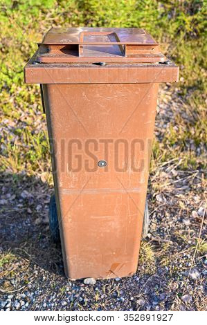 Gabage Can Standing Near A Gravel Road