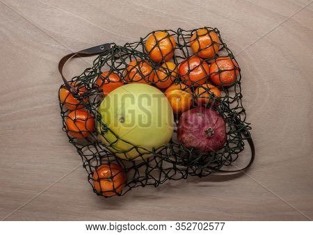 Mandarins, Pomelo, Pomegranate In Green Net Bag Zero Waste Concept Lay On Wooden Table
