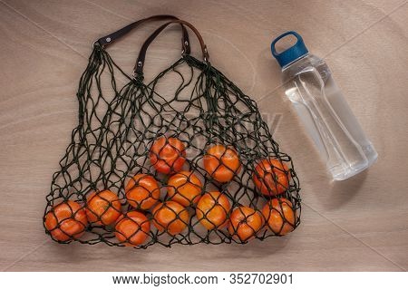 Mandarins In Green Net Bag Zero Waste Concept Lay On Wooden Table