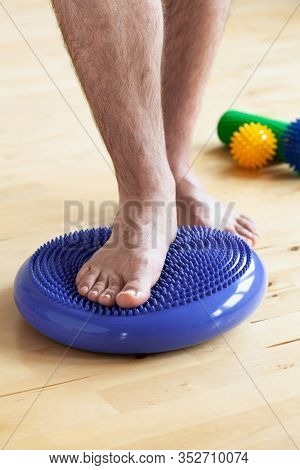 man doing flatfoot correction gymnastic exercise balancing on massage cushion at home