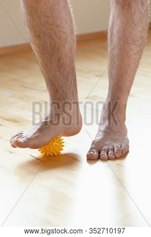 man doing flatfoot correction gymnastic exercise using massage ball at home