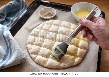 Hand Is Coating Flat Bread Dough With An Egg Yolk Mixtur, Baking In The Style Of The Turkish Ramadan