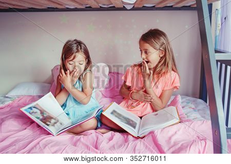 Surprised Scared Caucasian Sisters Girls Reading Books In Bedroom. Home Schooling Children Siblings 