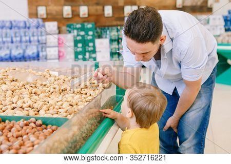 Caucasian Father Shopping In Grocery Store With Baby Son. Man With Kid Buying Nuts. Dad Parent Teach