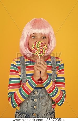 Sweet Tooth. Little Child Hold Lollipop Candy Yellow Background. Small Girl With Rainbow Swirl Candy