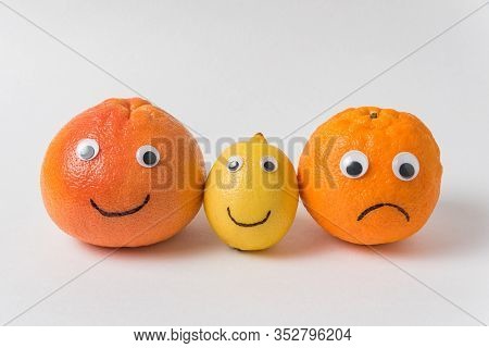 Grapefruit, Lemon And Orange With Funny Faces On White Background. Optimist And Pessimist Concept.