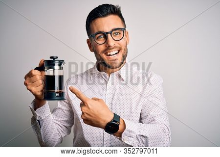 Young handsome man making coffee using french press coffeemaker over isolated background very happy pointing with hand and finger