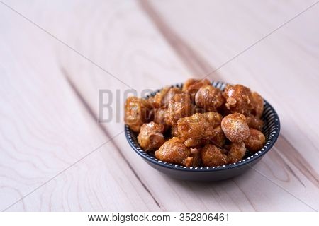 closeup of a plate with some nueces de macadamia garrapinadas, spanish candied macadamia nuts, on a wooden table
