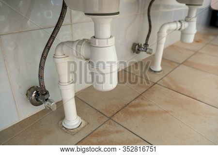 Close Up Of White Plastic Pipe Drain Under Washing Sink In Bathroom.