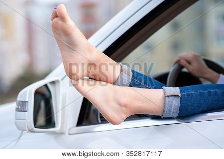 Close Up Of Woman Driver Bare Feet Sticking Out Of A Car Open Window.