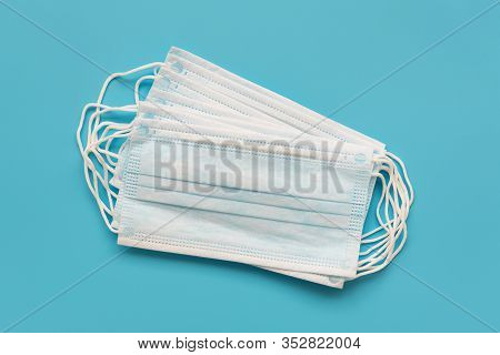 Several Surgical Ear-loop Masks Lying On Blue Background. Top View. Protection Concept