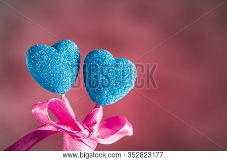 Marmalade In Sugar Blue In The Form Of Hearts On Sticks With A Bow On A Light Pink Background
